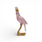 Swarovski Crystal Paradise Cockatoo Pink figure mounted on wooden perch, designed by Roland Schuster