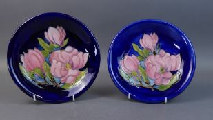 Moorcroft plates in the Magnolia pattern on blue ground. (Largest Dia: 21.5cm) (2)