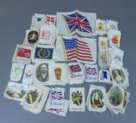 A collection of small silks, featuring various flags and pictures , some embroidered , some