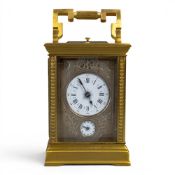 A carriage clock housed in case, crest etched to both glass sides, date edged to glass on top 1888 -