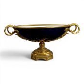 An oval porcelain serving bowl with cobalt exterior, with ornate gilt metal mounts, handle to handle