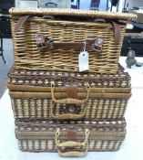Three Picnic Baskets each one have leather style fasteners and some picnic ware contents.