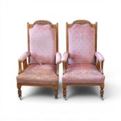 A pair of high-backed library chairs with pink velour upholstery and carved wood detailing along the