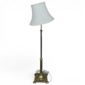 Early 20th century brass floor lamp with slender polished column rising from a heavy square base.