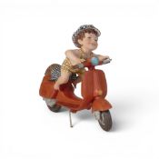 European Porcelain Depicting A Child Wearing A Yellow and Brown Plaid Outfit Riding A Red Scooter.
