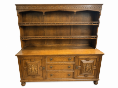 A traditional Jacobean - style solid oak Welsh dress featuring two carved cabinet doors & three cent