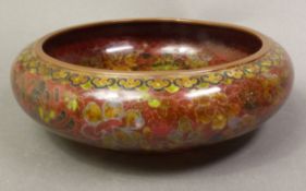 Chinese cloisonné centre bowl with floral decoration on a red/brown ground, diameter 23cm.