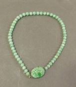 A vintage light green jade bead necklace with a carved matching jade centrepiece clasp.