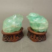 Two carved green fluorite figures of chicks, raised on pierced hardwood stands, overall height