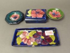 Four Moorcroft Hibiscus pattern items on blue and green ground including lidded trinket box, trinket