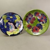 Two Moorcroft chargers, one Anemone design on green and one Clematis on cobalt blue ground, diameter