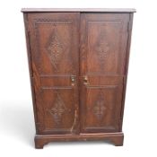 Priory style dark oak folding door cupboard, carved details, internal shelving and door pocket. (