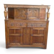 Jacobean-style carved oak court cupboard featuring intricate foliate carvings, upper and lower