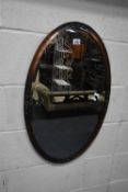 AN OVAL COPPER FRAMED BEVELLED EDGE WALL MIRROR, 73cm x 46cm, condition report: patina to frame