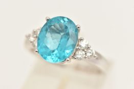 AN 18CT WHITE GOLD GEM SET RING, set with an oval cut blue stone, possibly apatite, flanked with