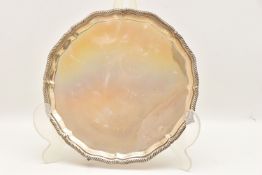 A GEORGE V SILVER SALVER, circular wavy form with gadrooned rim raised on four talon feet,