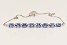 AN 18CT WHITE GOLD TANZANITE AND DIAMOND LINE BRACELET, designed as a series of eight oval cut