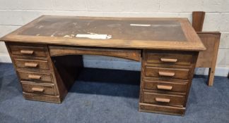 AN EARLY 20TH CENTURY OAK DESK, with a leatherette writing surface, fitted with eight drawers and