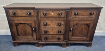 A GEORGIAN OAK BREAKFRONT DRESSER BASE, fitted with six assorted drawers, two cupboard doors, raised
