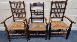 THREE EARLY 20TH CENTURY RUSH SEATED CHAIRS, with turned spindles to the backrest, open armrests,