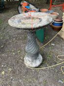 A CONCRETE BIRDBATH, with a spiral fluted base, height 79cm. Condition Report: weathering to bowl,