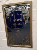 A GOLD PAINTED WOODEN RECTANGULAR WALL MIRROR, reading Grand Hotel, surrounded by scrolled patterns,