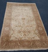 A RED AND CREAM GROUND RECTANGULAR WOOLLEN RUG, with repeating foliate patterns, surrounded by a