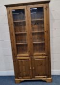 A DUCAL PINE CABINET, the double glass doors enclosing three adjustable glass shelves, over double