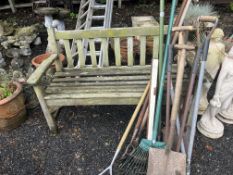 A HARDWOOD GARDEN BENCH, with slatted seat and back, 129cm wide, along with various garden tools,