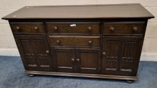 AN ERCOL DARK ELM AND BEECH CANTERBURY SIDEBOARD, fitted with four assorted drawers and two pairs of