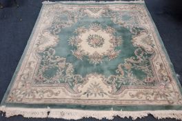 A LARGE TEAL GROUND RECTANGULAR CHINESE WOOLLEN RUG, with foliate patterns, surrounded by a multi-