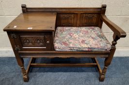 AN OLD CHARM OAK TELEPHONE SEAT, with linenfold details, a single cupboard door, raised on block and