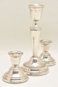 A PAIR OF SILVER DWARF CANDLESTICKS AND ONE SINGLE STICK, the dwarf candlesticks on round weighted