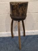 A PRIMITIVE CYLINDRICAL CHOPPING BLOCK, with an iron banding, raised on three legs Dimensions:height
