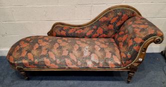 A VICTORIAN CHAISE LONGUE, with a scrolled armrest, foliate upholstery, raised on cylindrical