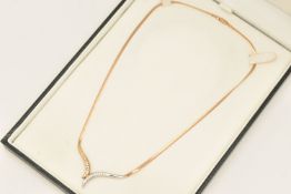 A 9CT GOLD DIAMOND SET PENDANT NECKLACE, designed as a bi-colour V-shape pendant chanel set with