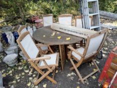 A FOLDING HARDWOOD GARDEN TABLE, oval in shape and 150cm long, along with six folding chairs, a