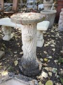 A CONCRETE GARDEN ORNAMENT in the form of a tree stump base with a platter atop and a squirrel