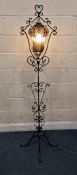 A WROUGHT IRON STANDARD LAMP, with scrolled details, and a blown glass shade that's cradled in a