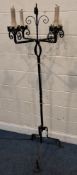 A WROUGHT IRON ECCLESIASTICAL STYLE STANDARD LAMP, in the form of a candle stand, with candle-shaped