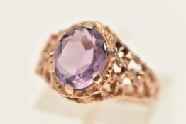 A 9CT GOLD AMETHYST SET RING, set with an oval cut amethyst, six claw set to the textured open