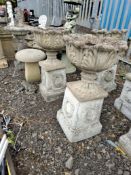A PAIR OF CONCRETE GARDEN URNS ON STANDS with acanthus leaf detail to bowls, square bases with