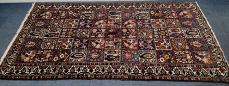 A MULTI-COLOURED RECTANGULAR WOOLLEN RUG, the fifty-five square grid with various patterns,