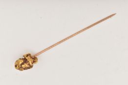 A GOLD NUGGET SITCK PIN, designed as a rough gold nugget fitted with a yellow metal pin, approximate