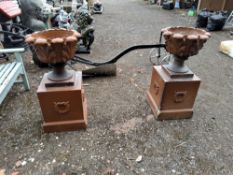 A PAIR OF EARLY 20th CENTURY TREACLE GLAZED URNS ON STANDS with acanthus leaf detail to bowls,