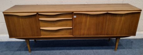 A STONEHILL MID-CENTURY TEAK SIDEBOARD, fitted with two cupboard doors, a fall front door and