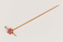 A YELLOW METAL GEM SET STICK PIN, set with a circular cut ruby in a scallop setting and a small
