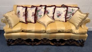 A REPRODUCTION LARGE TWO SEATER SOFA, with yellow striped upholstery, scrolled armrests, raised on