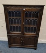 A JAYCEE OAK BOOKCASE, with double lead glazed doors over double linenfold cupboard doors