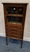 AN EDWARDIAN MAHOGANY MUSIC CABINET, fitted with a single glass door over four fall-front drawers,